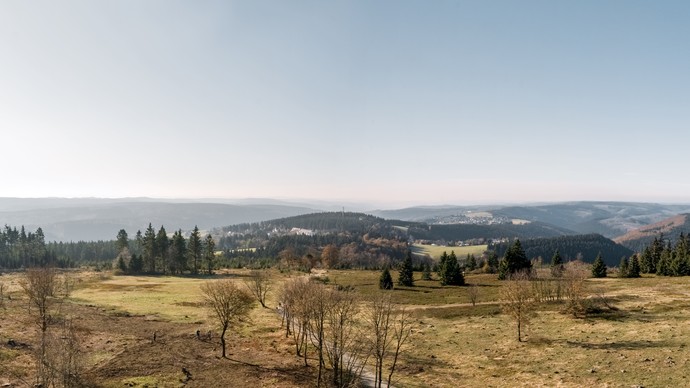 Blick über ein weites Tal vom Berg "Kahler Asten" aus über Heidefläche, Wanderwege und baumbewachsenen Bergen.