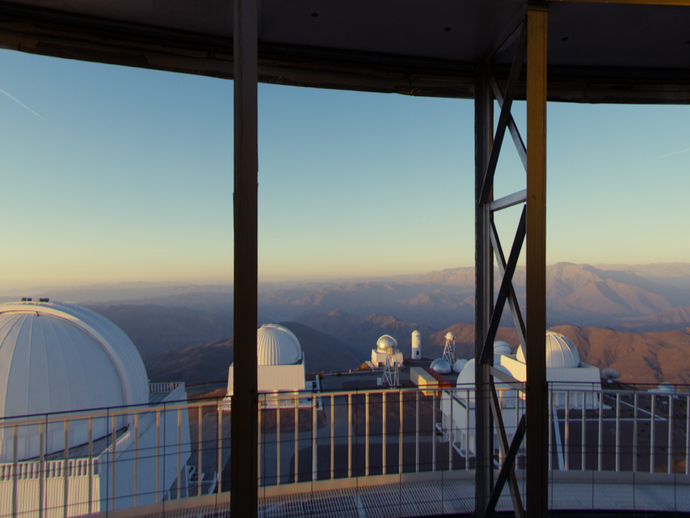 Viele weiße Observatoriumskuppeln vereint auf einer braunen Berglandschaft. (vergrößerte Bildansicht wird geöffnet)